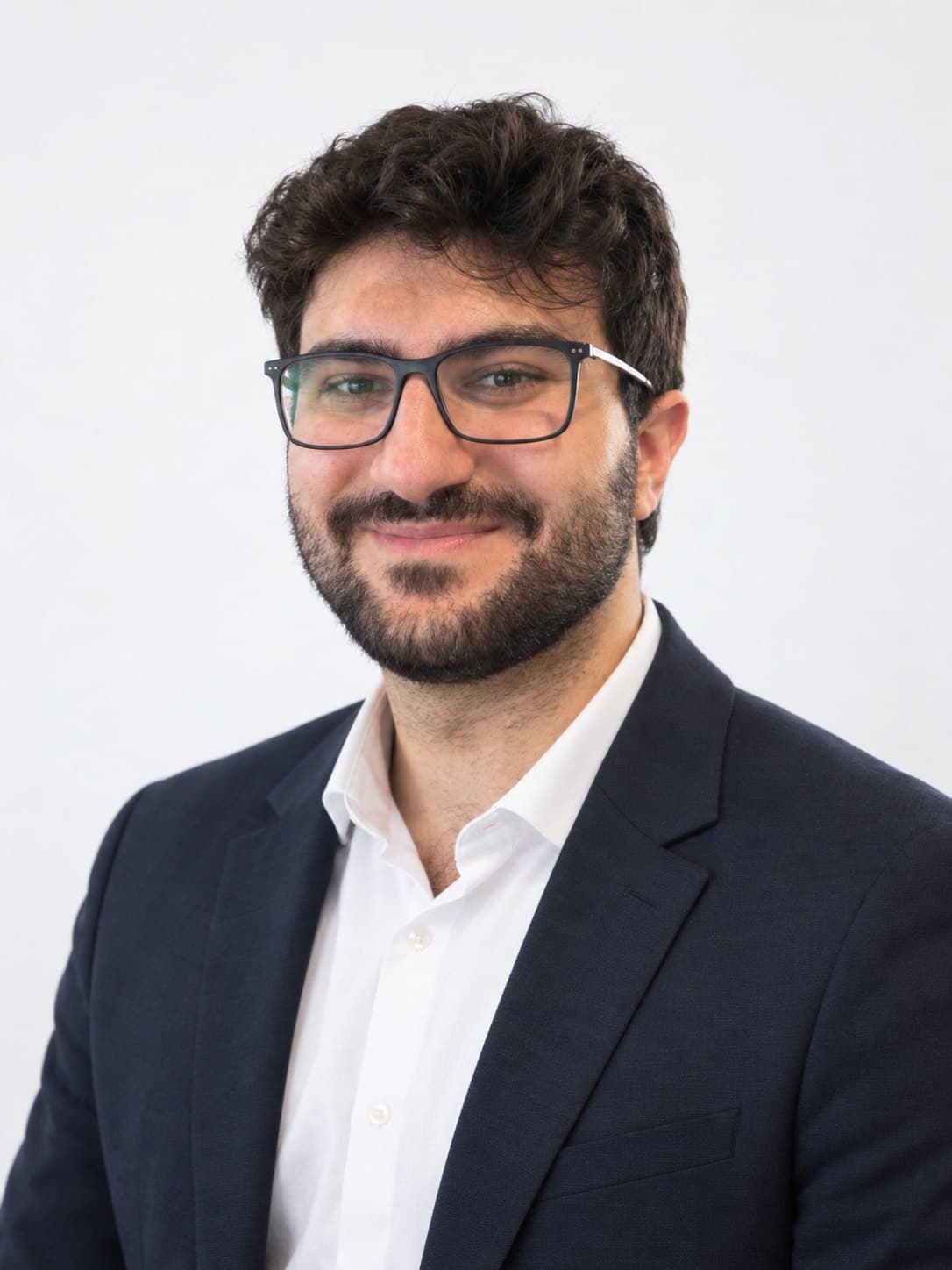 Portrait of Sari in a navy blazer, white shirt and glasses